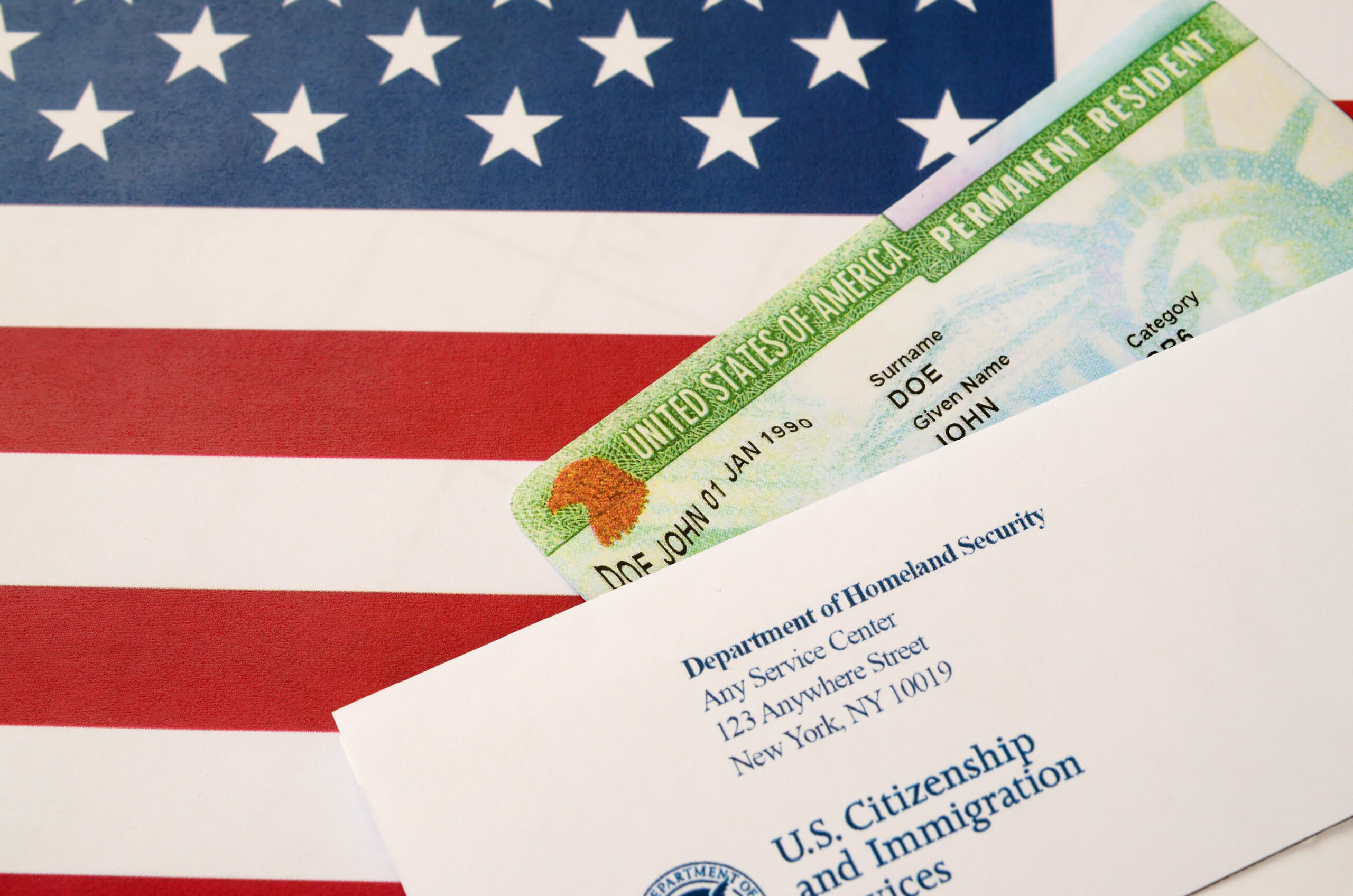 United States Permanent resident green card from dv-lottery lies on United States flag with envelope from Department of Homeland Security